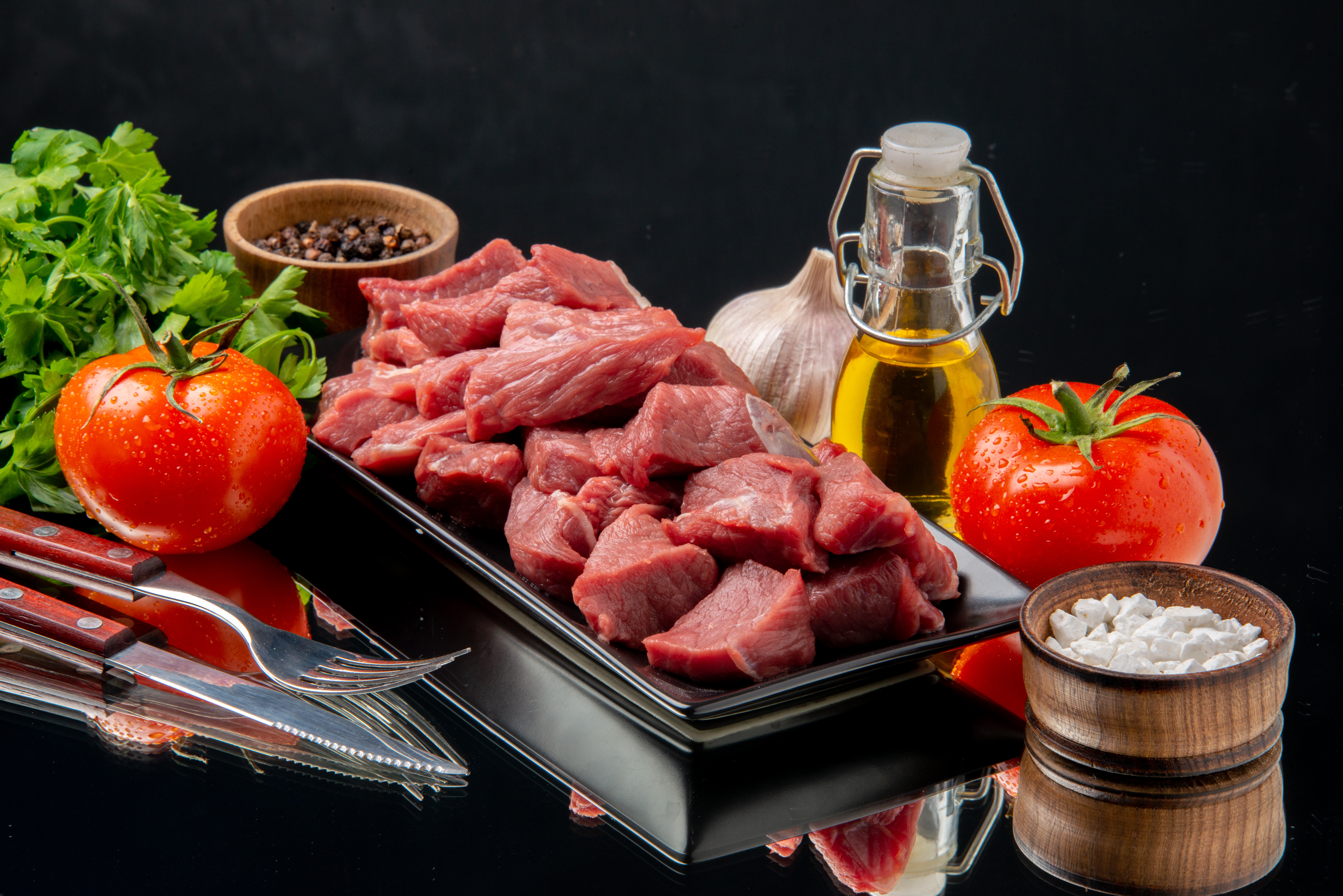 front-view-fresh-meat-slices-inside-black-tray-with-tomatoes-greens-black-table