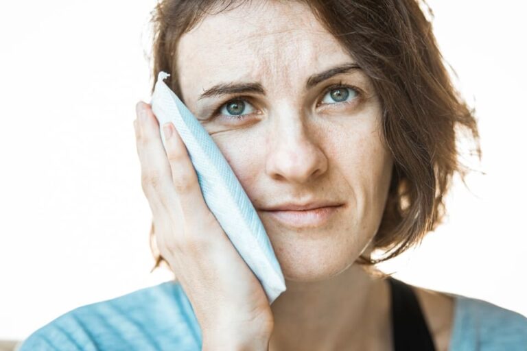 Person easing jaw pain with a cold pack — TMJ treatment at Mint Dental Care in Dubai